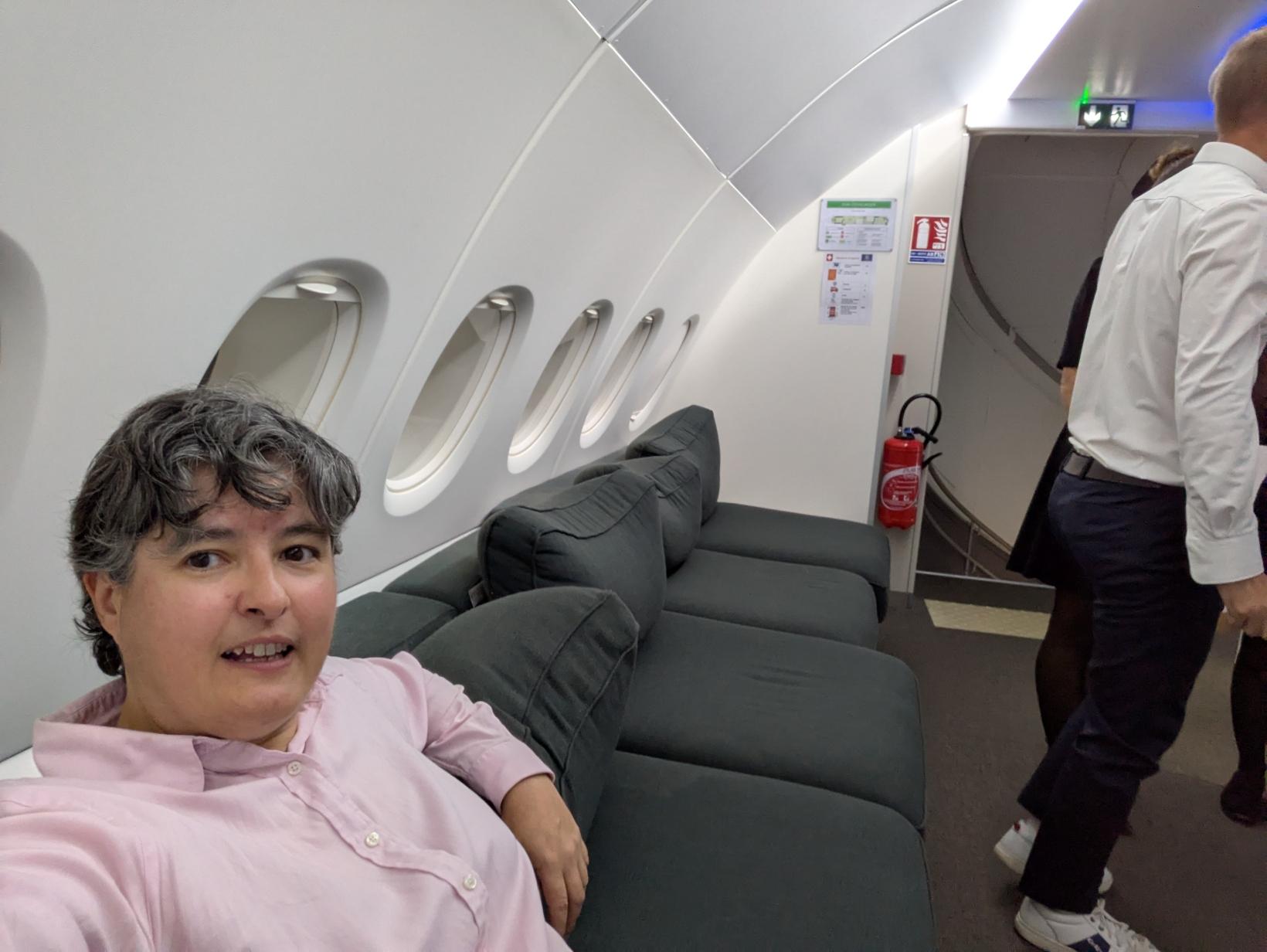 Selfie sur un immense canapé. il y a une rangée de hublots d'avion derrière le canapé. cette fois c'est vraiment dans un avion : l'A380 (étage haut) avec un aménagement grand luxe